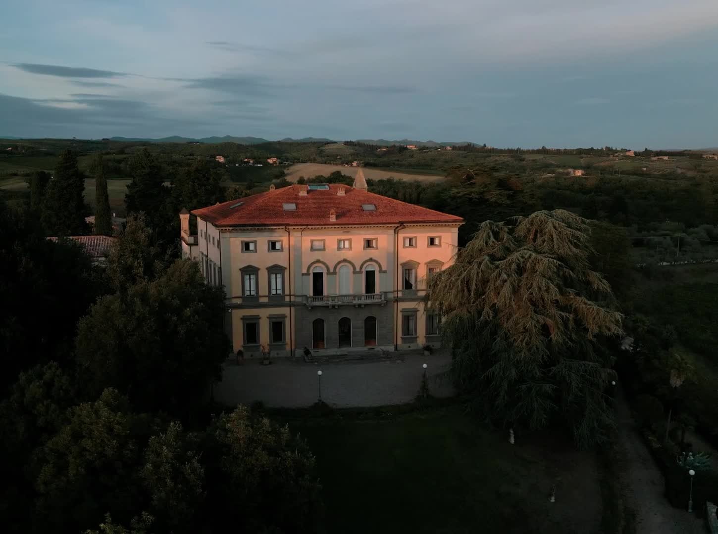 Aerial view of a grand Tuscan villa at golden hour surrounded by countryside